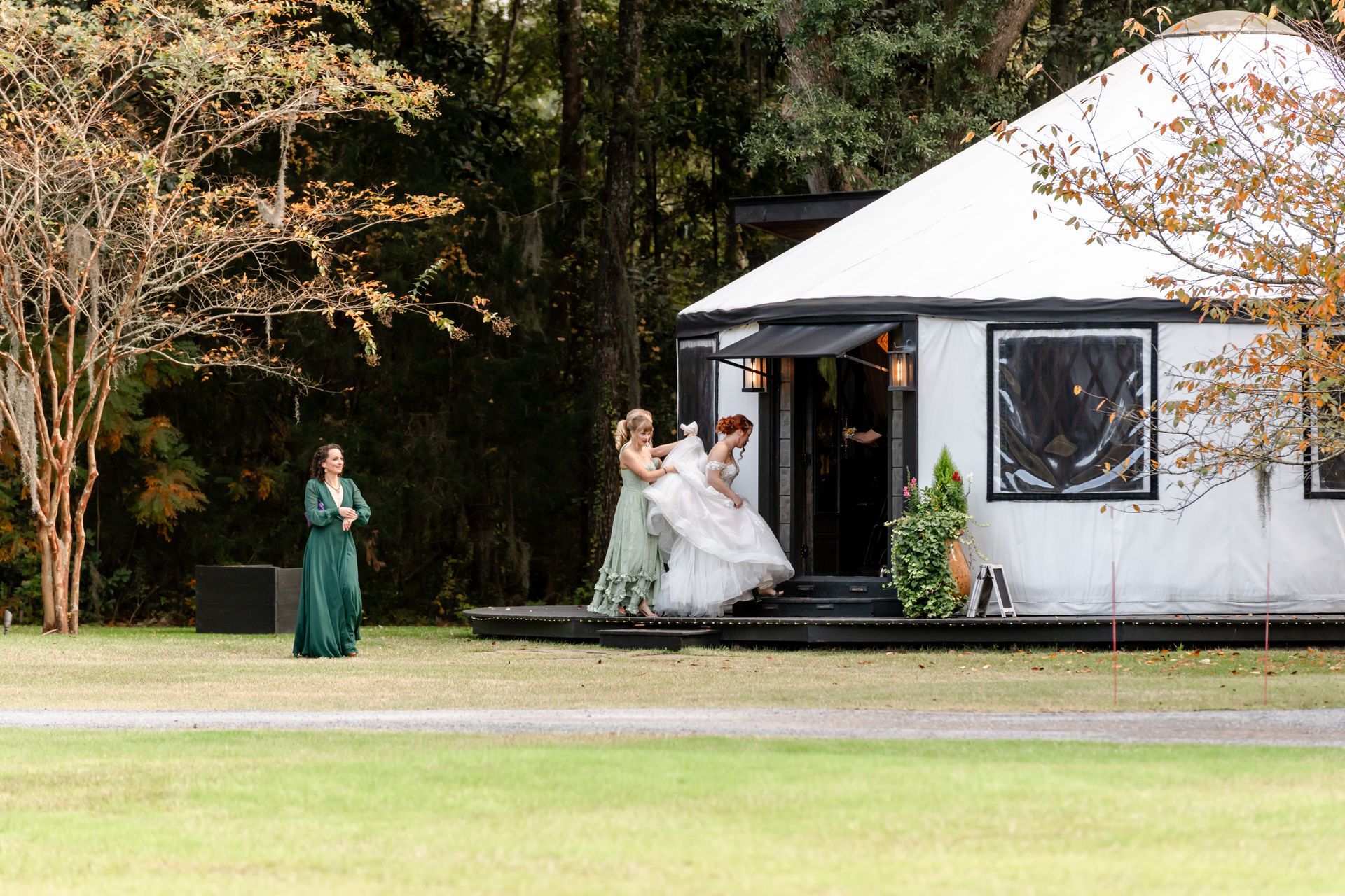 Bride and bridesmaid walking outside a white tent at an outdoor wedding venue