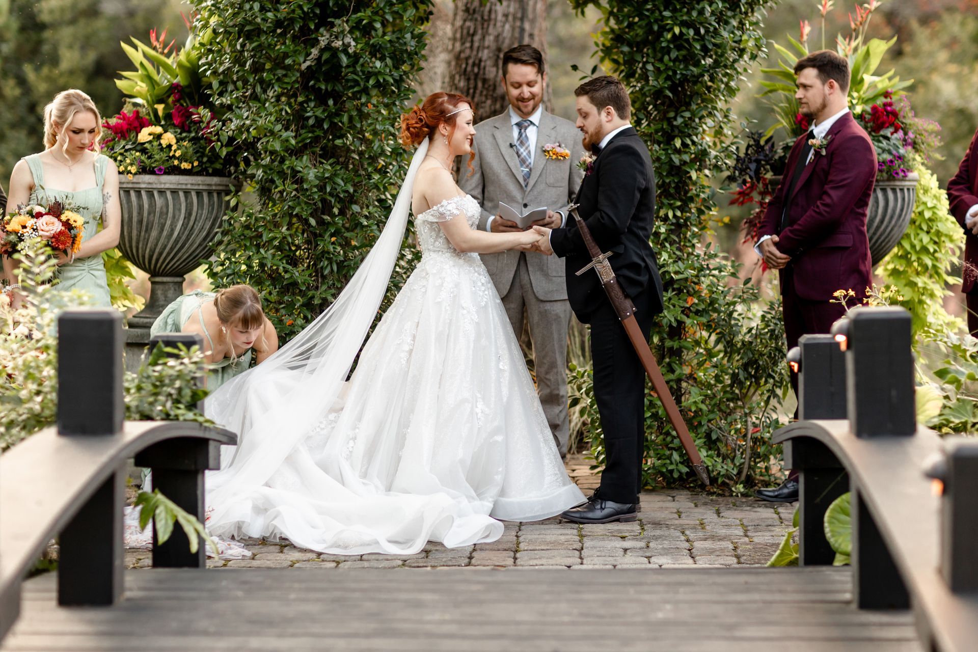 Wedding couple exchanges vows in an outdoor garden ceremony with guests and floral greenery.