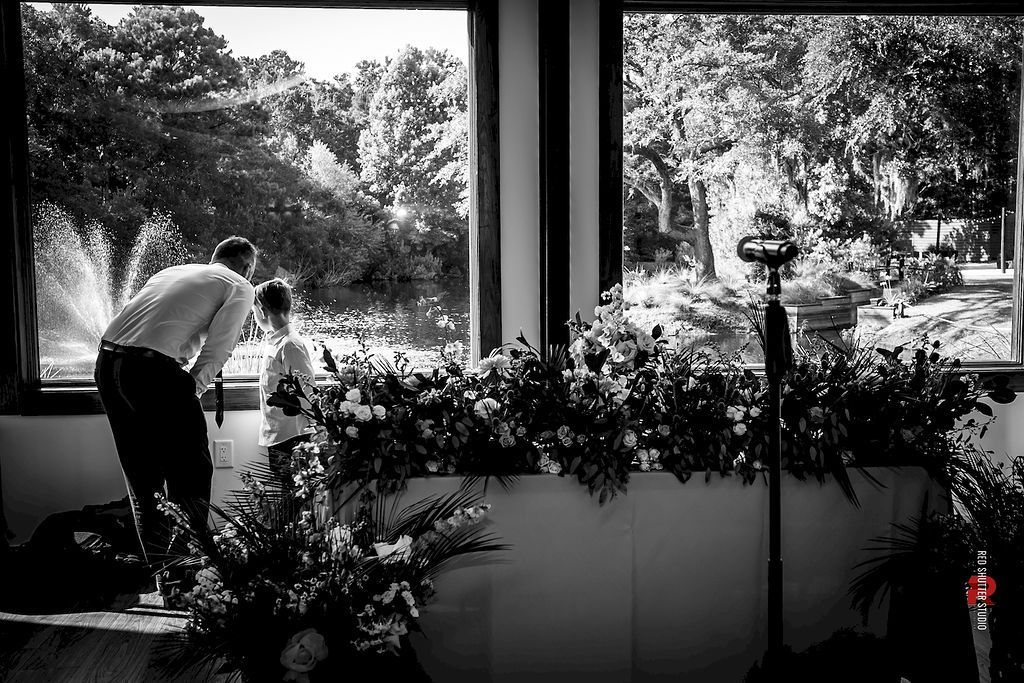 People arranging potted plants on a windowsill overlooking a garden