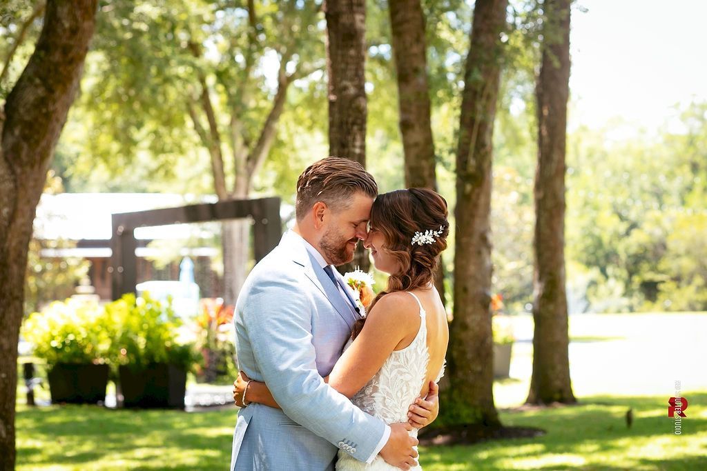 Couple embracing outdoors in a sunlit park with trees and flowers