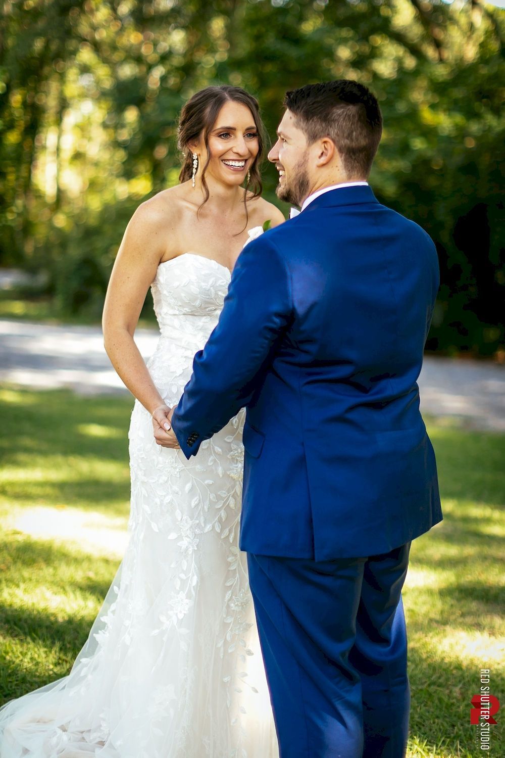 Bride and groom holding hands outdoors, smiling in a sunny garden