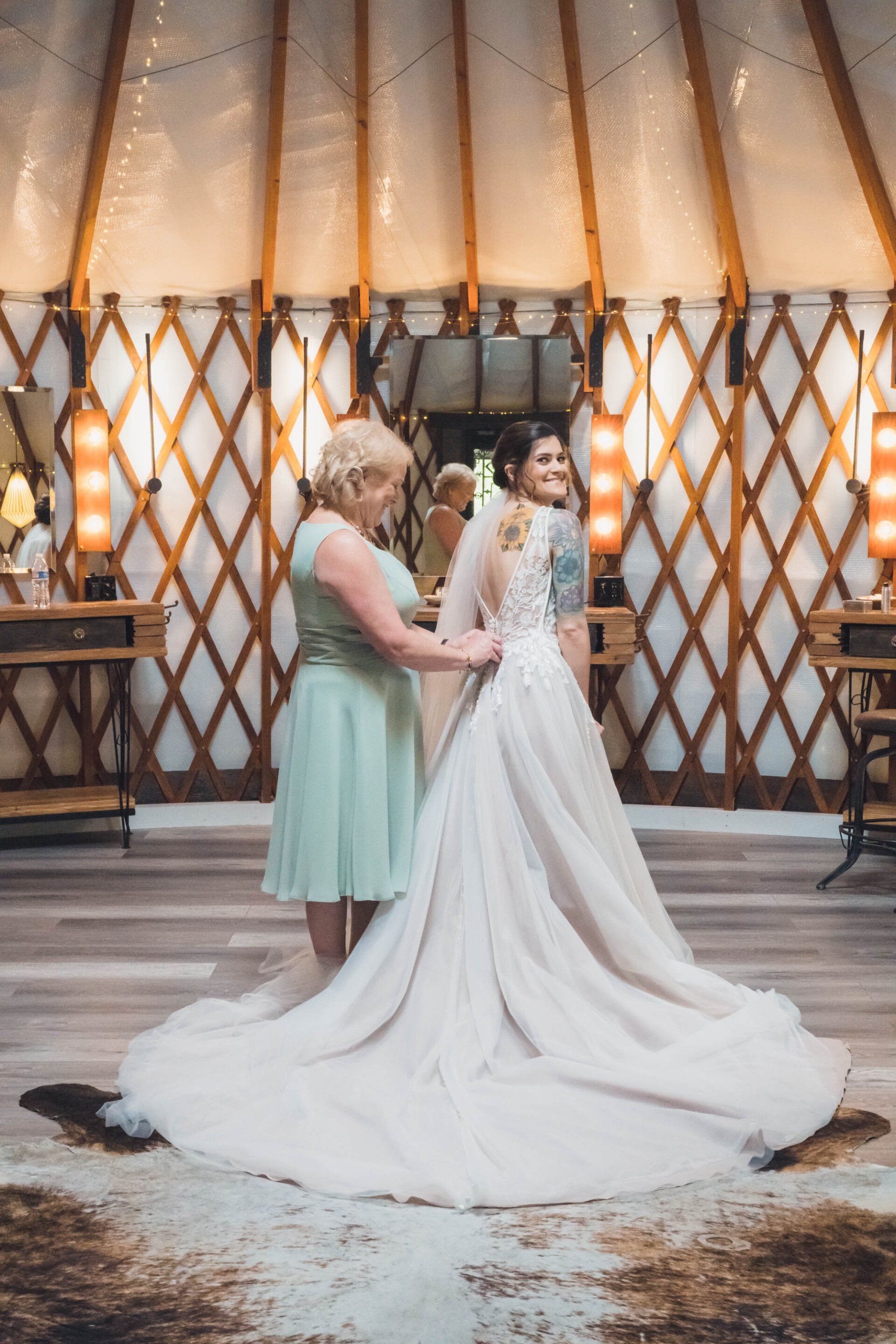 Bride in white gown with attendant in mint dress at a rustic wedding ceremony backdrop