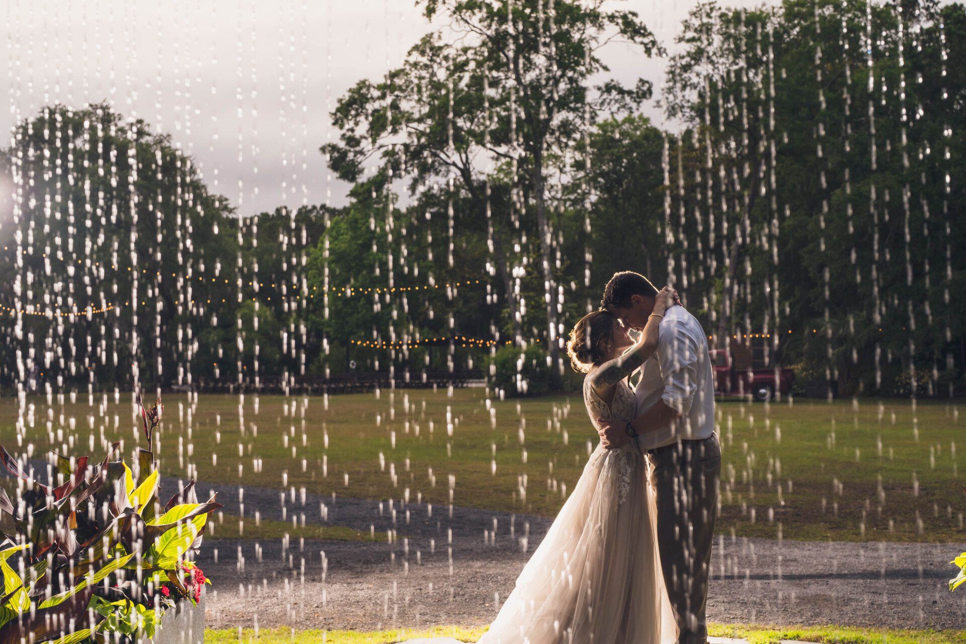 Couple embracing behind a curtain of water at sunset in a grassy park
