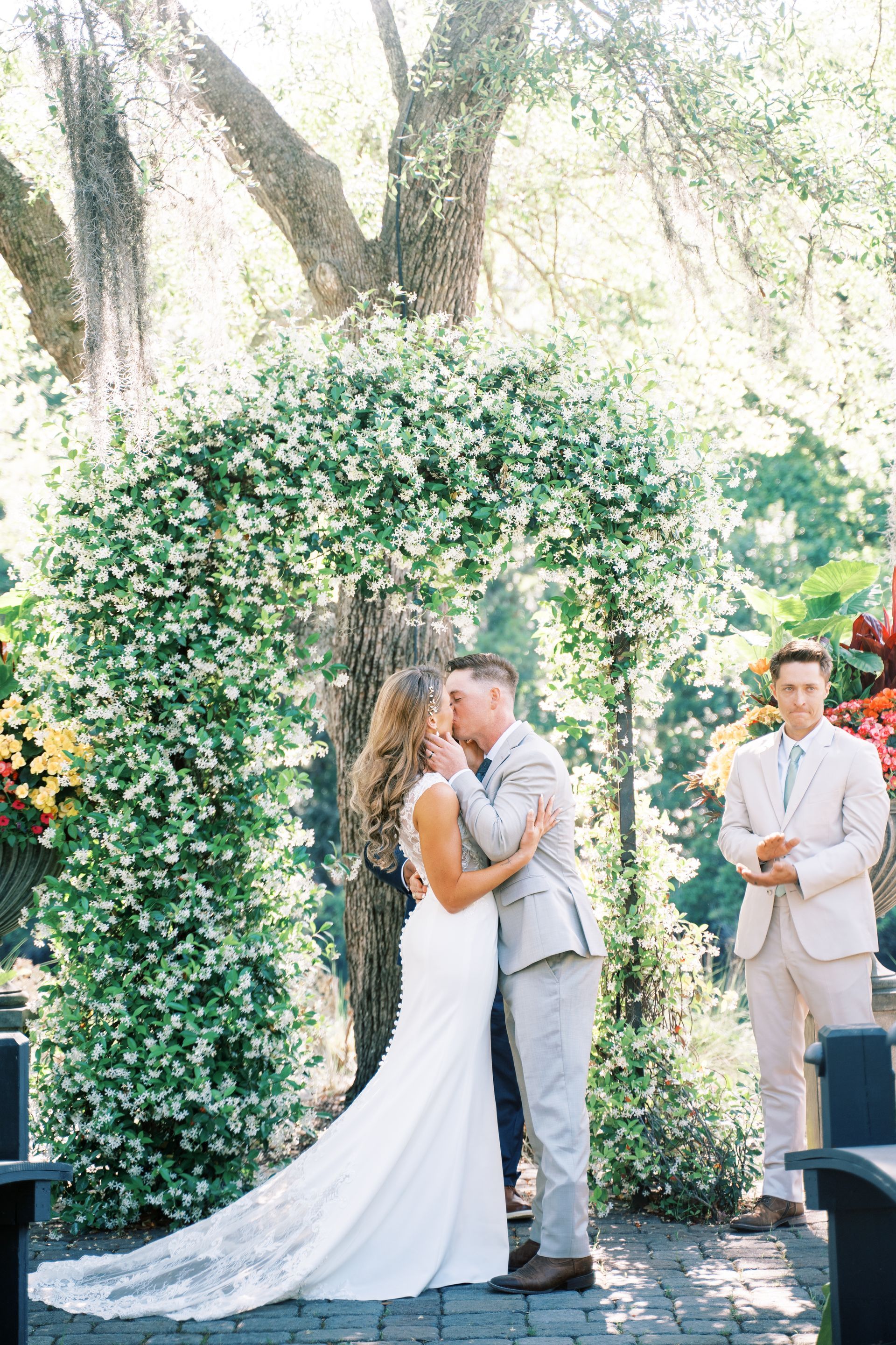 Wedding couple kissing under a flower-covered arch outdoors
