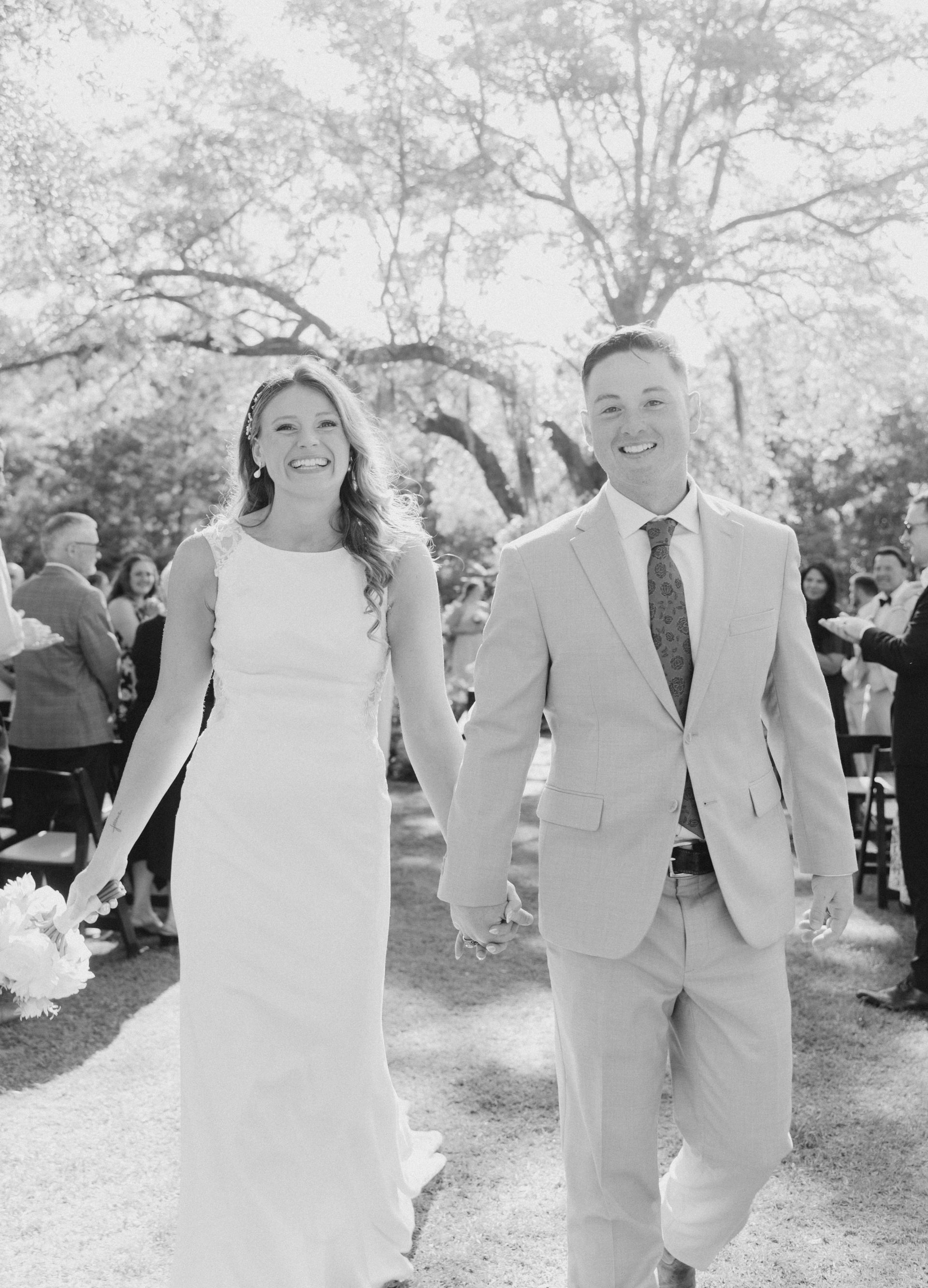 Bride and groom walking hand in hand outdoors at a wedding ceremony