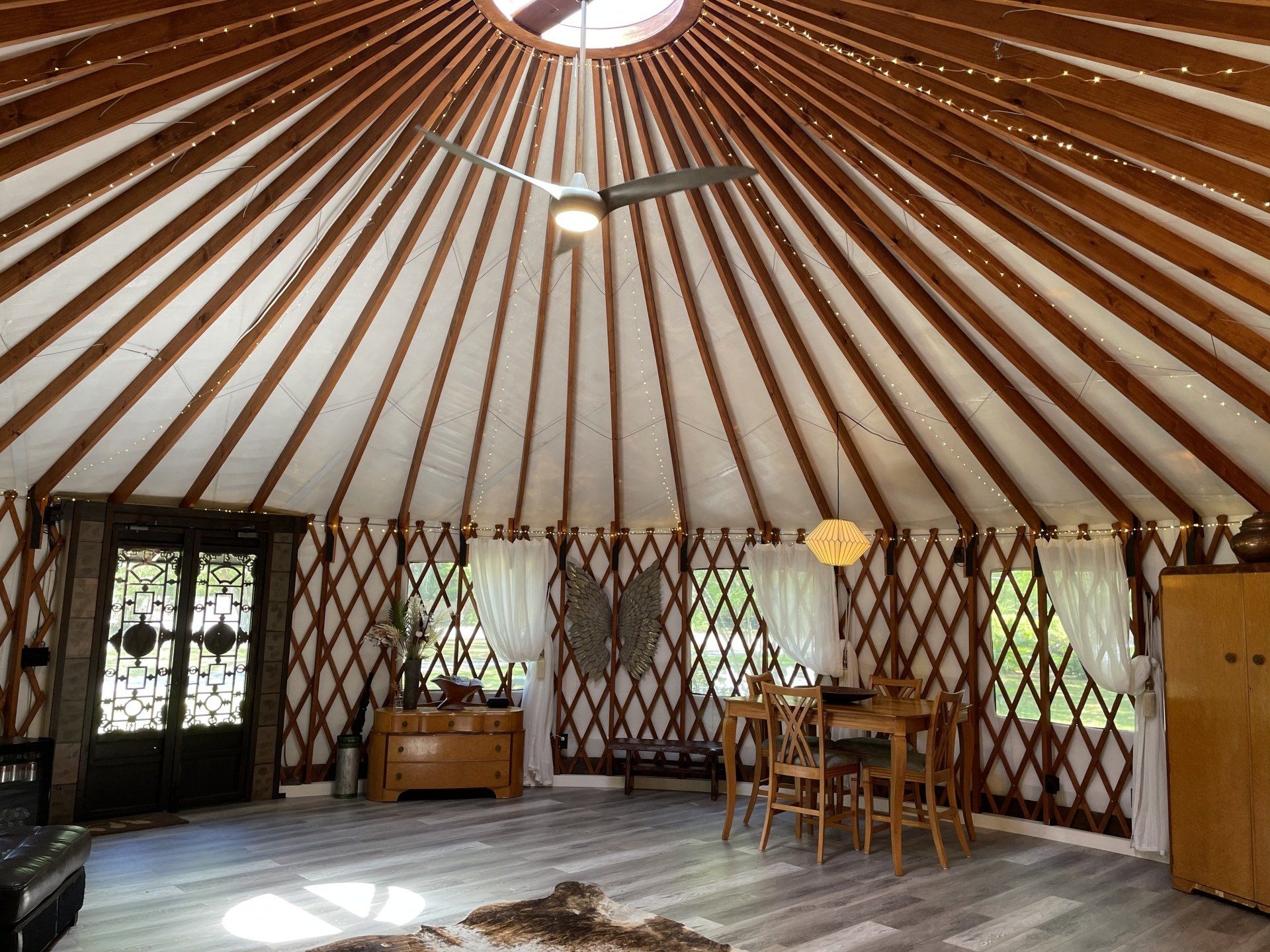 Interior of a round yurt with wooden ribs, windows, and a small table and chairs on the floor