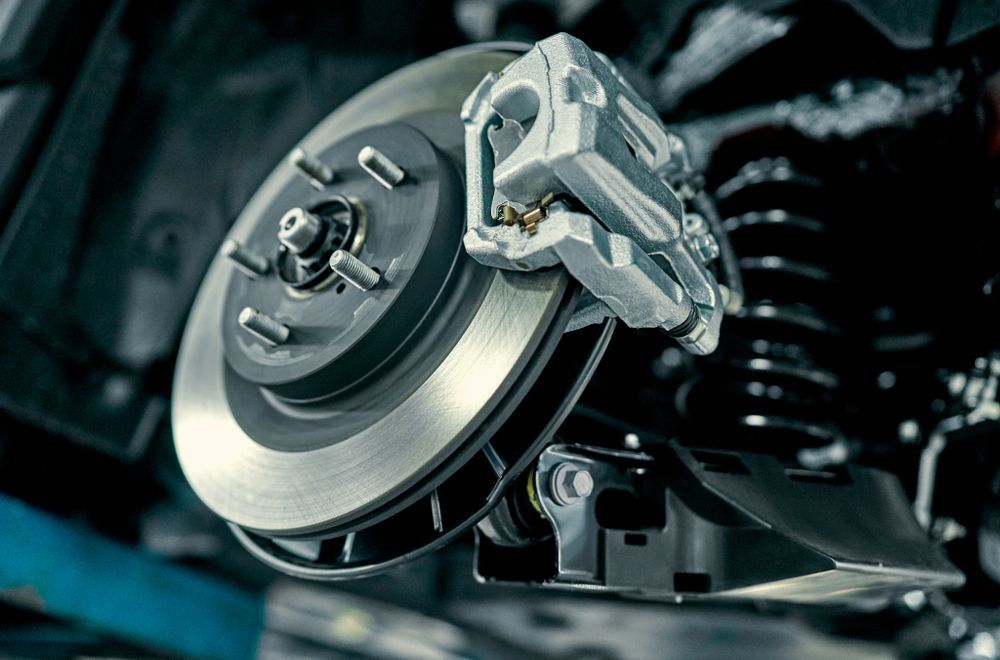 Close-up of a car's disc brake system, showing a silver rotor, brake caliper, and other mechanical components.