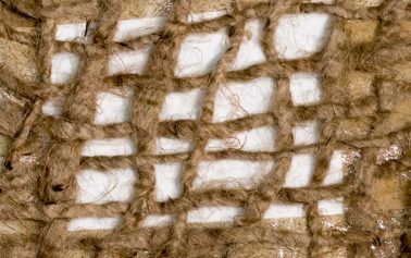 Close-up of white woven threads on a brown textured fabric background