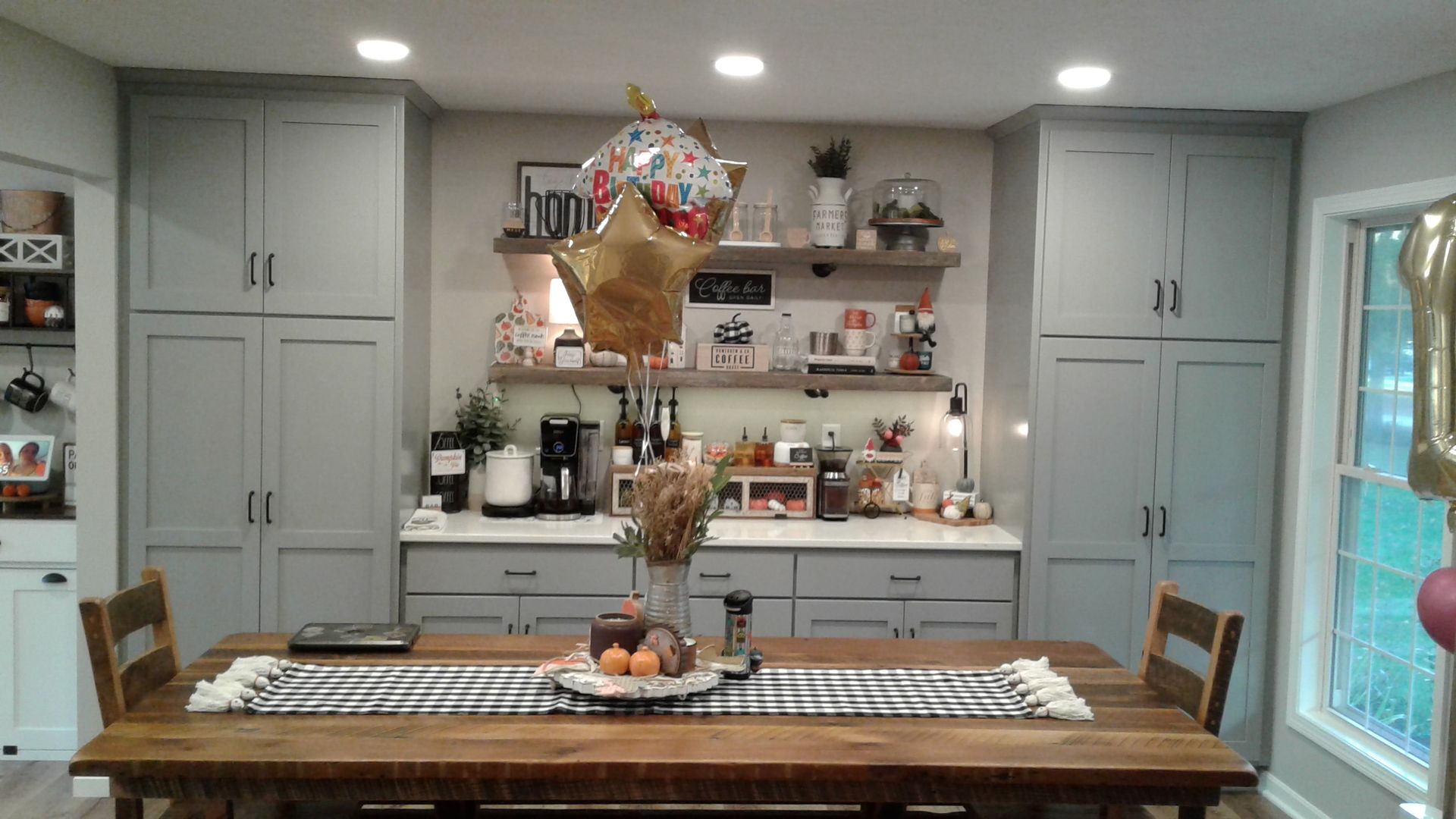 Kitchen with grey cabinets, wooden table set for meal, with a balloon.