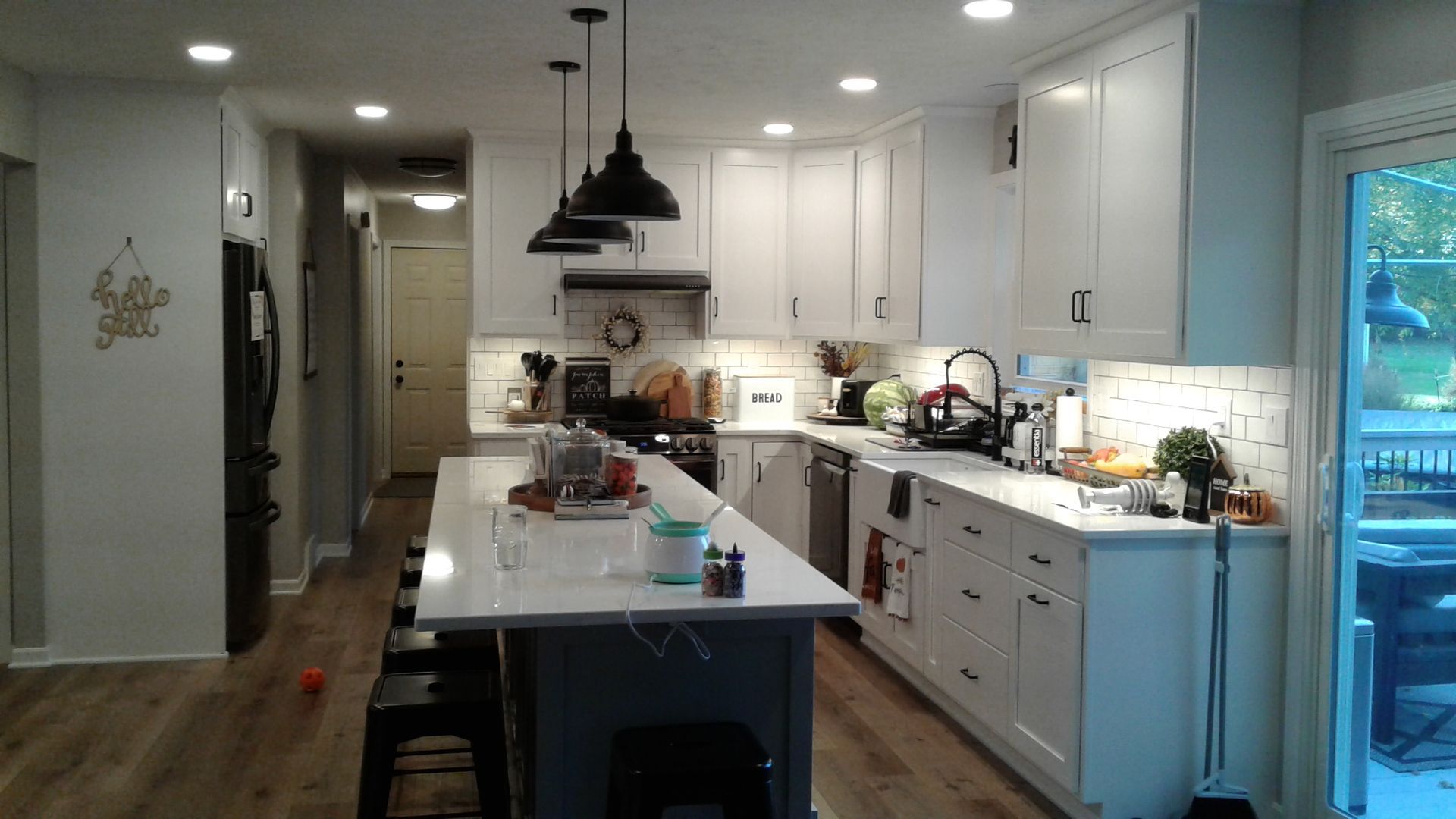 Modern kitchen with white cabinets, dark island, and pendant lights.