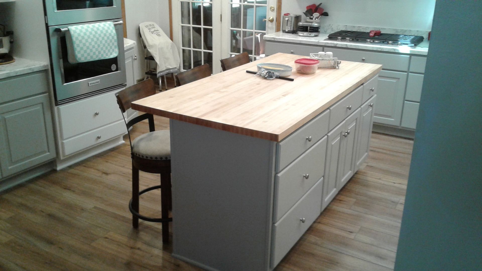 Kitchen with a light-wood countertop island, gray cabinets, and wooden floors.