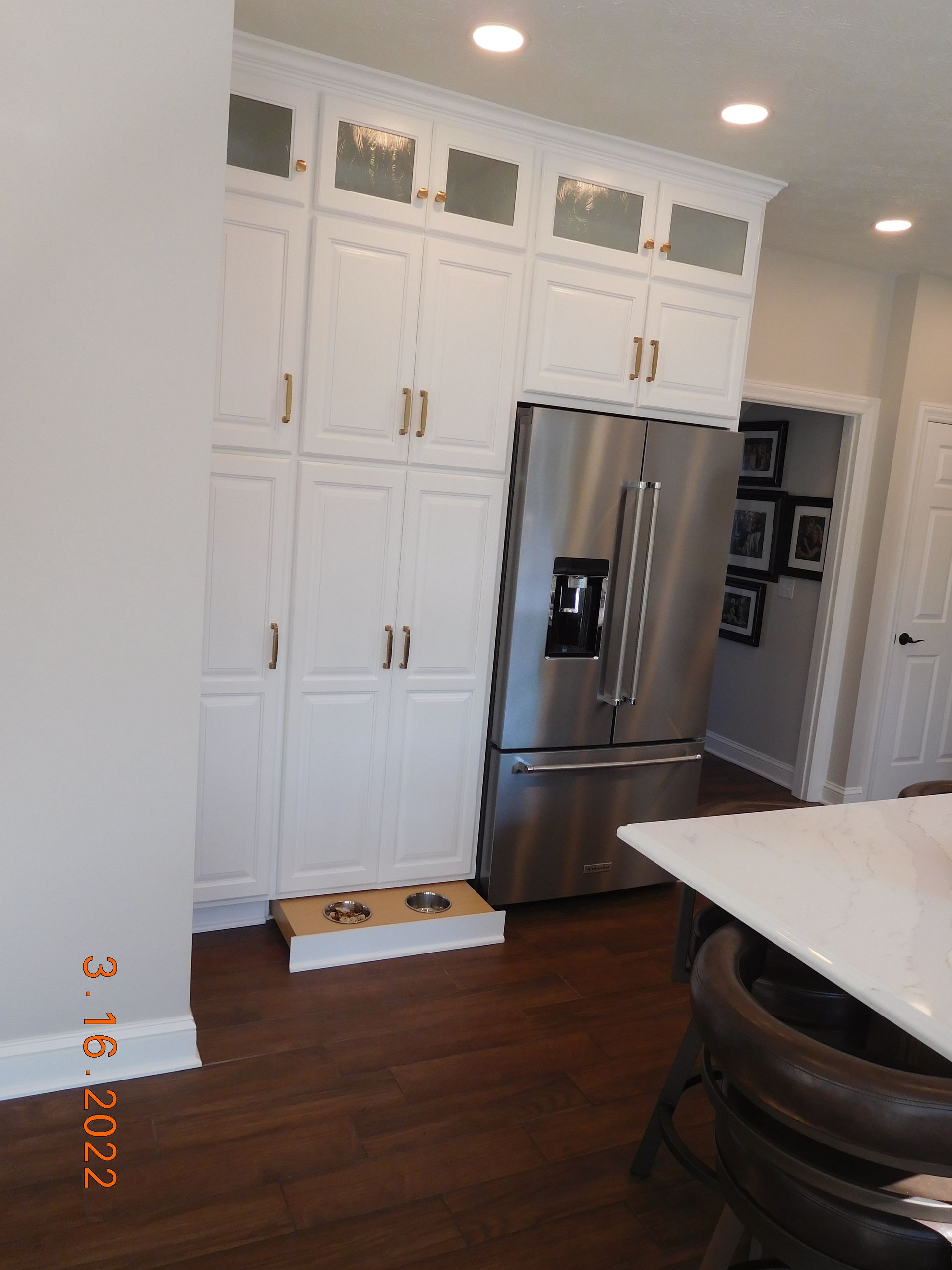White kitchen cabinets with stainless steel refrigerator and open doorway.