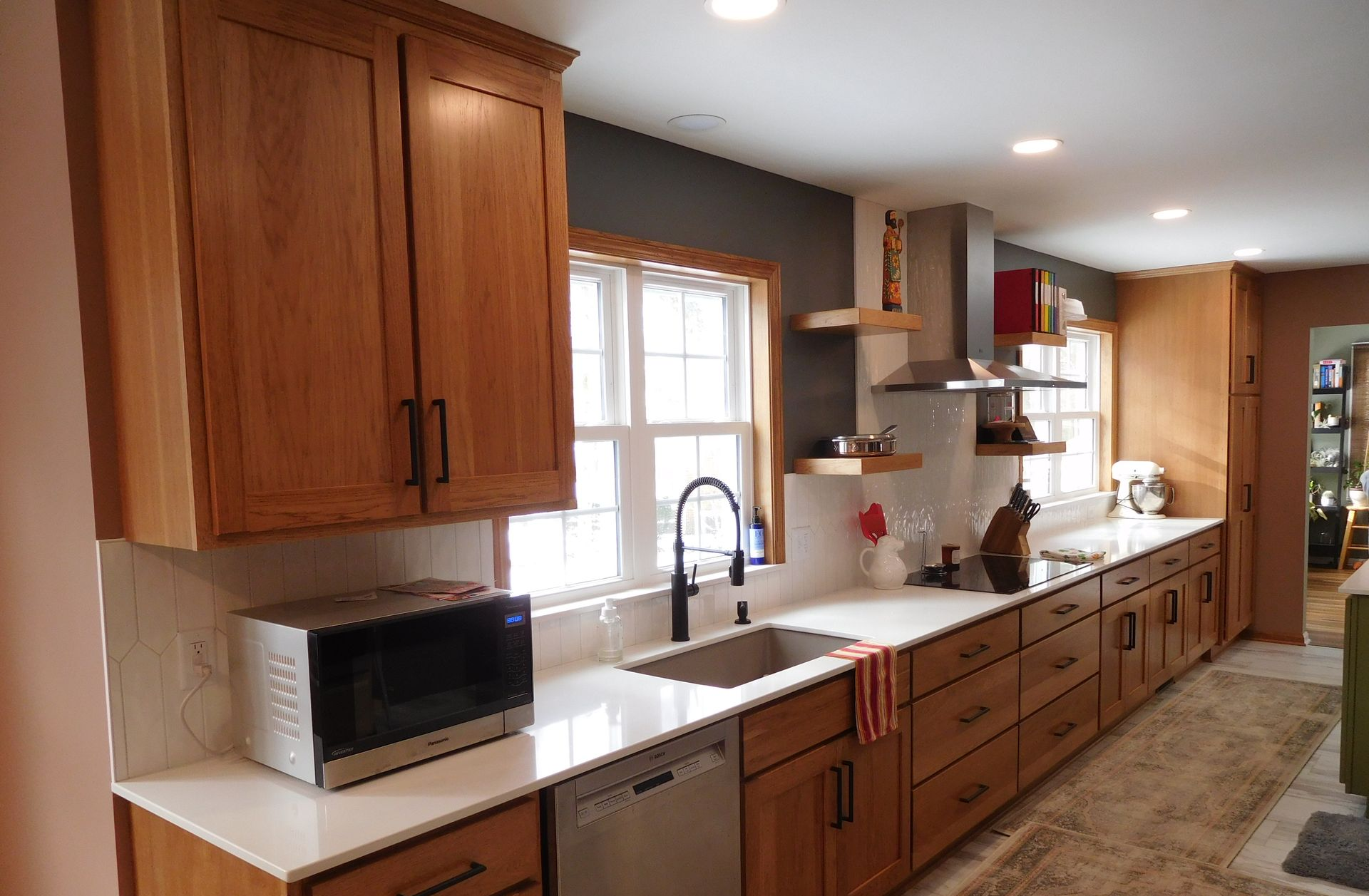 Kitchen with light wood cabinets, white countertops, dark gray backsplash.