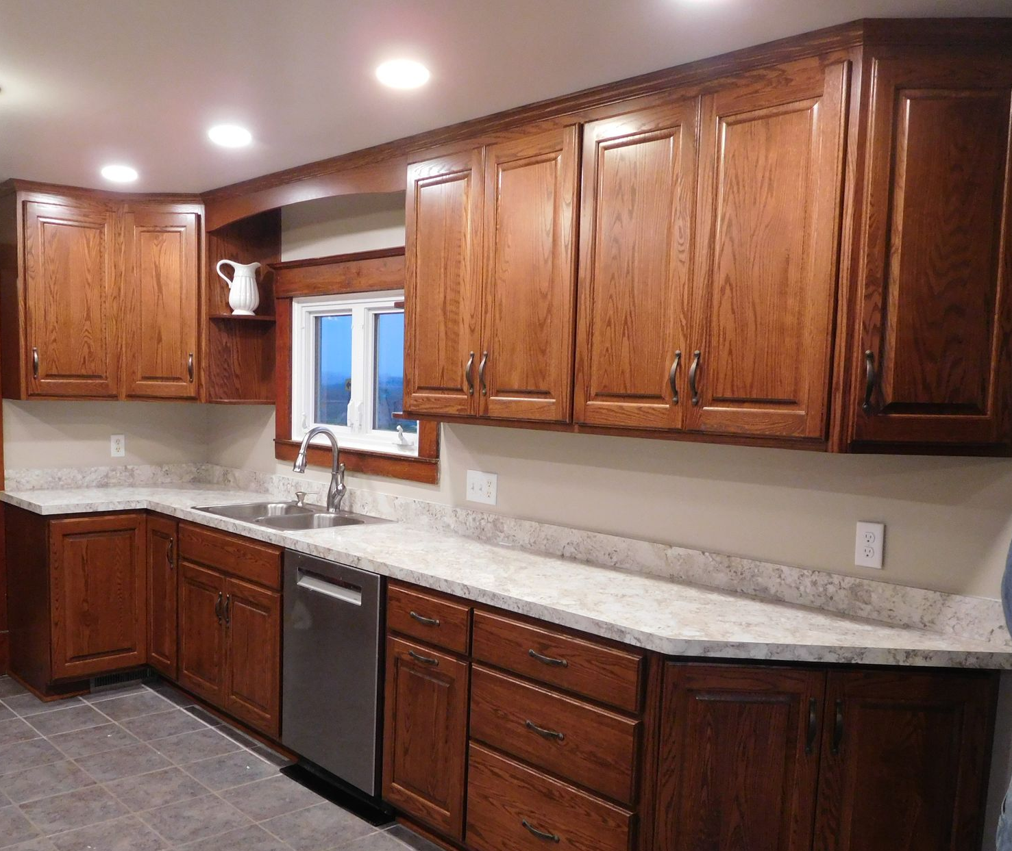 Kitchen with brown wooden cabinets, white countertops, and a stainless steel sink.