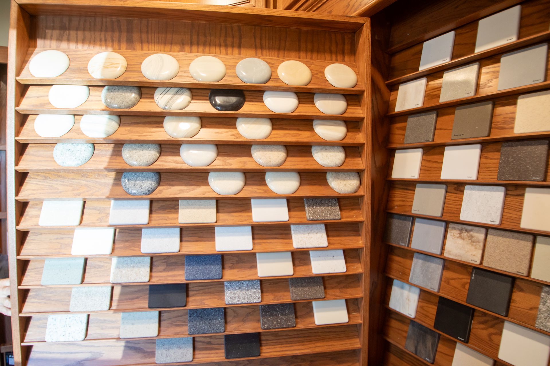 Display of various stone and tile samples in a wooden cabinet, showcasing color and texture options.
