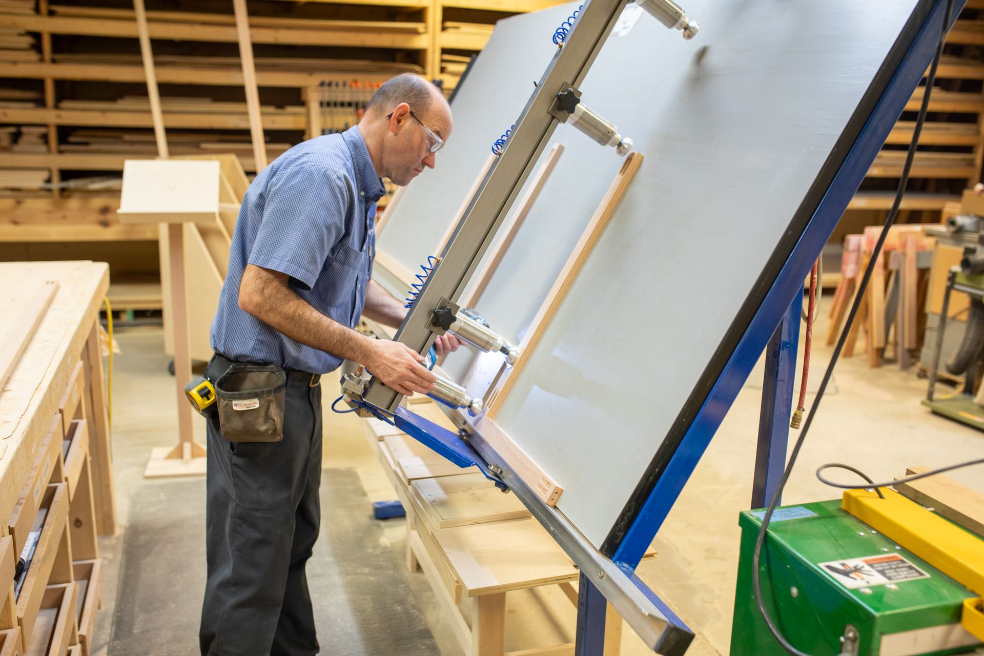 Man using a cutting machine on a wooden frame in a workshop.