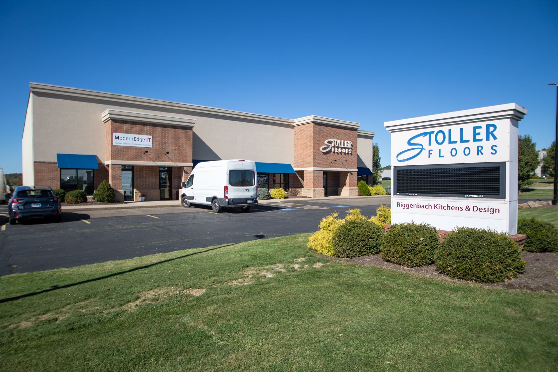 Exterior of Stoller Floors building with a sign and a van parked in front.