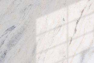 White marble surface with subtle grey veining, shadow of a window.