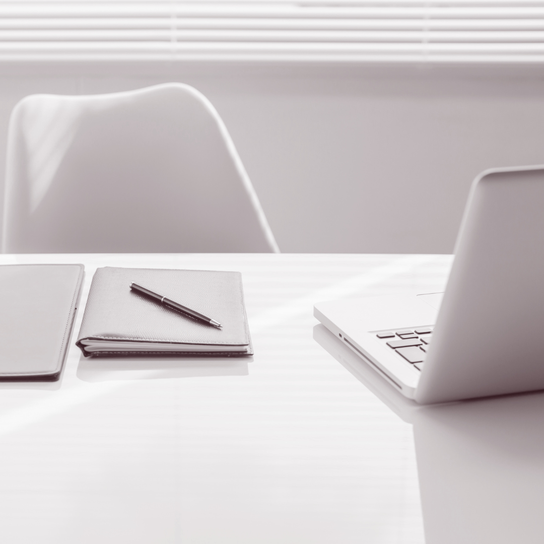 A laptop is sitting on a desk next to a notebook and pen