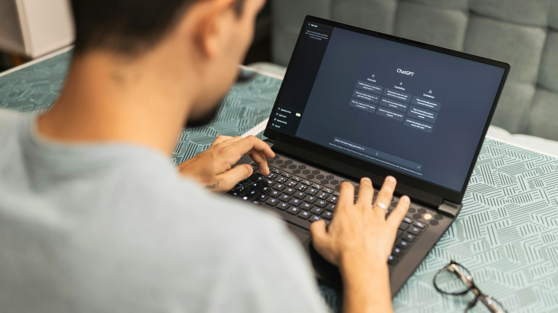 A man is typing on a laptop computer on a table.