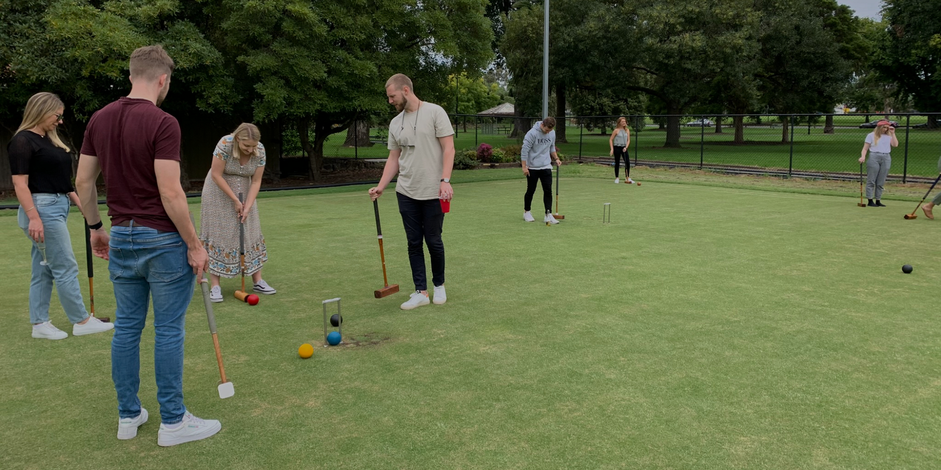 A group of people are playing croquet in a park.