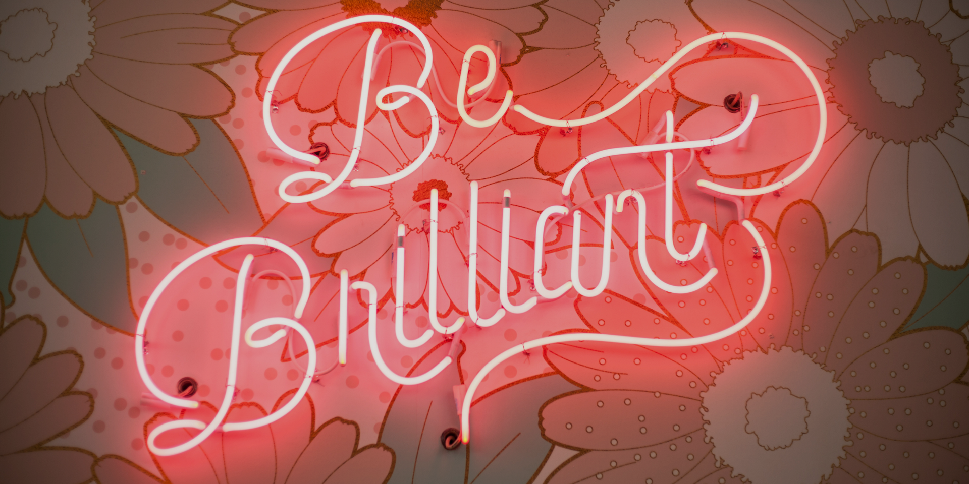 A neon sign that says `` be brilliant '' is hanging on a wall.