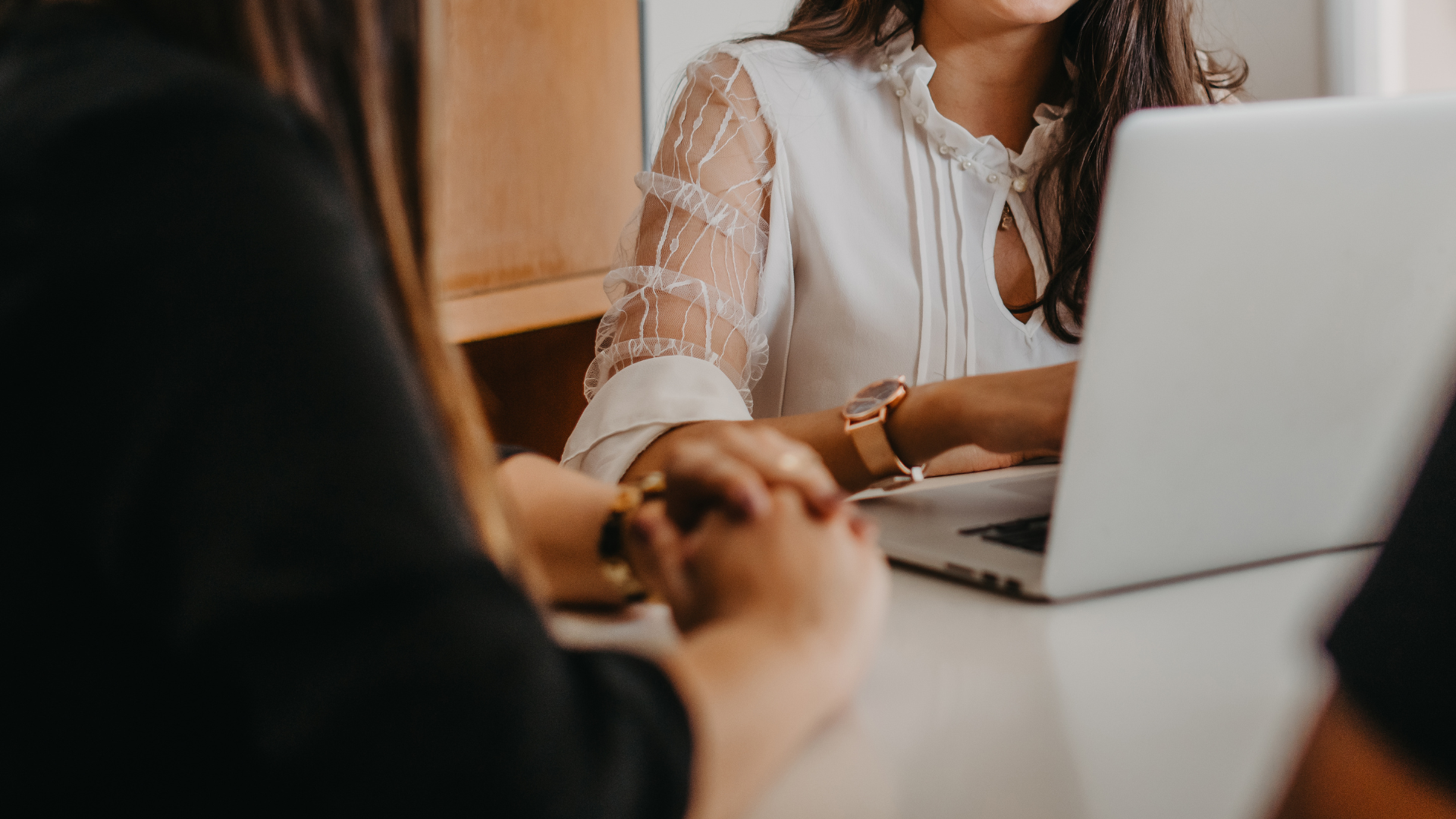 People in a meeting with a woman using a laptop at a table