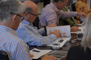 A group of people are sitting at a table looking at papers