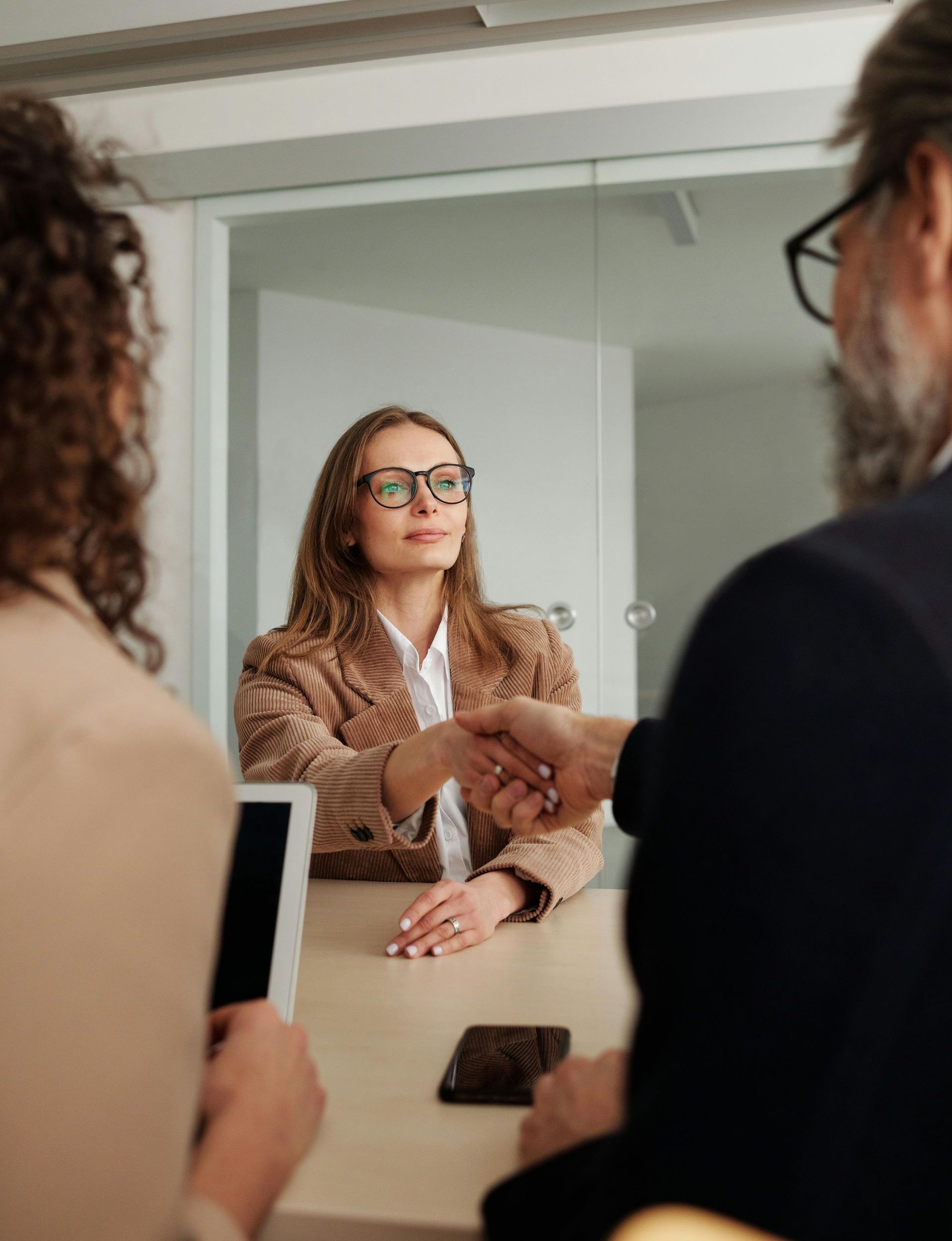 A woman is shaking hands with a man during a job interview.