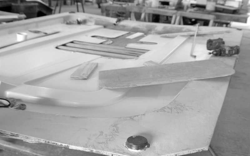 Close-up of a small tabletop model with a clear curved piece and wooden parts on a workbench