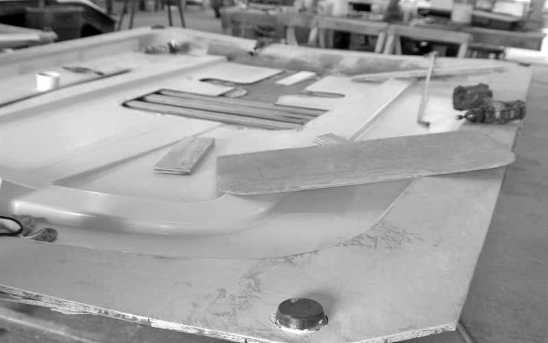 Black-and-white photo of a tabletop model with small objects, ramps, and a hexagonal bolt in the foreground