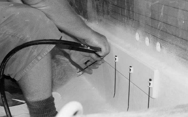 Worker using a hose to spray or clean the inside of a concrete tank or trough