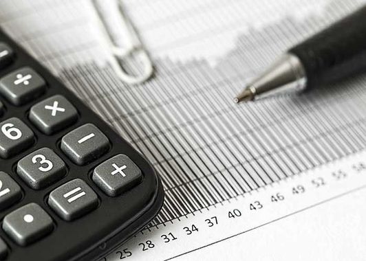 Calculator and pen on a financial ledger, suggesting accounting or budgeting.