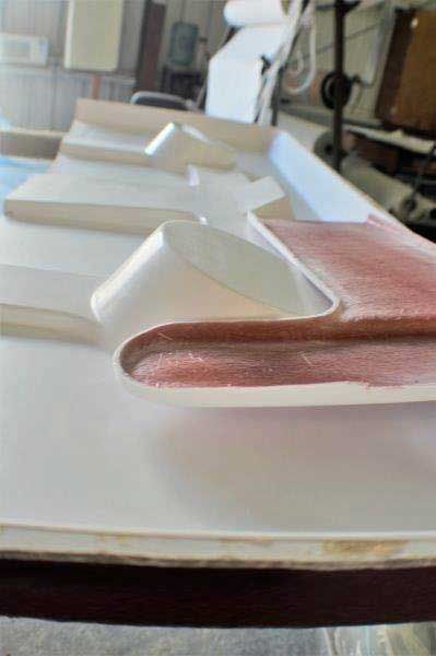 Close-up of a white table with several plastic samples, including a red textured strip and white angled pieces.