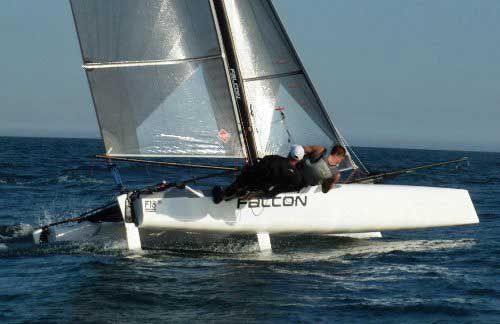 White sailing catamaran “FALCON” racing on choppy blue water under gray sails