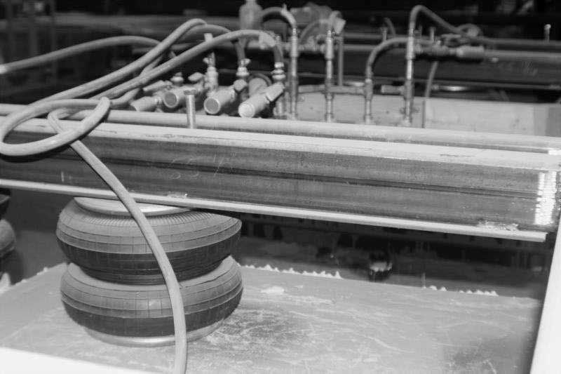 3D printer extruding a layered round object with tubes and rails in a workshop