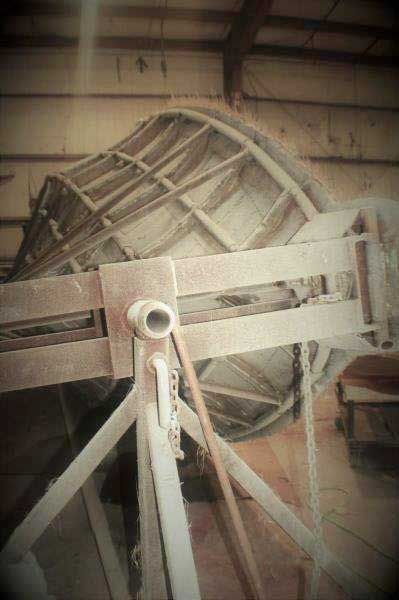 Large wooden wheel or pulley mechanism in a dim industrial interior