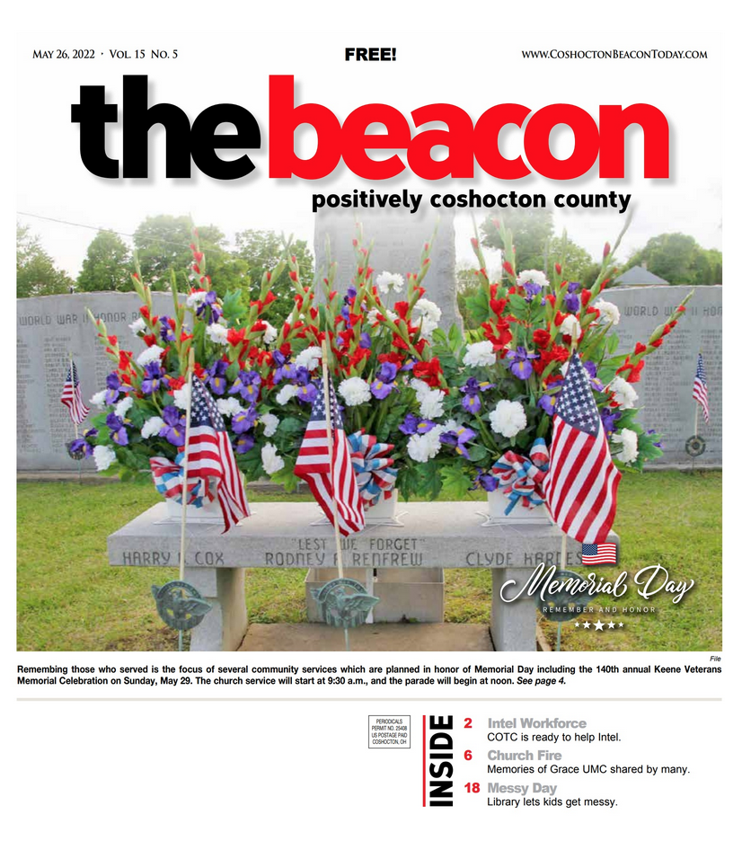 The cover of The Beacon newspaper showing floral arrangements and American flags on a stone memorial for Memorial Day.