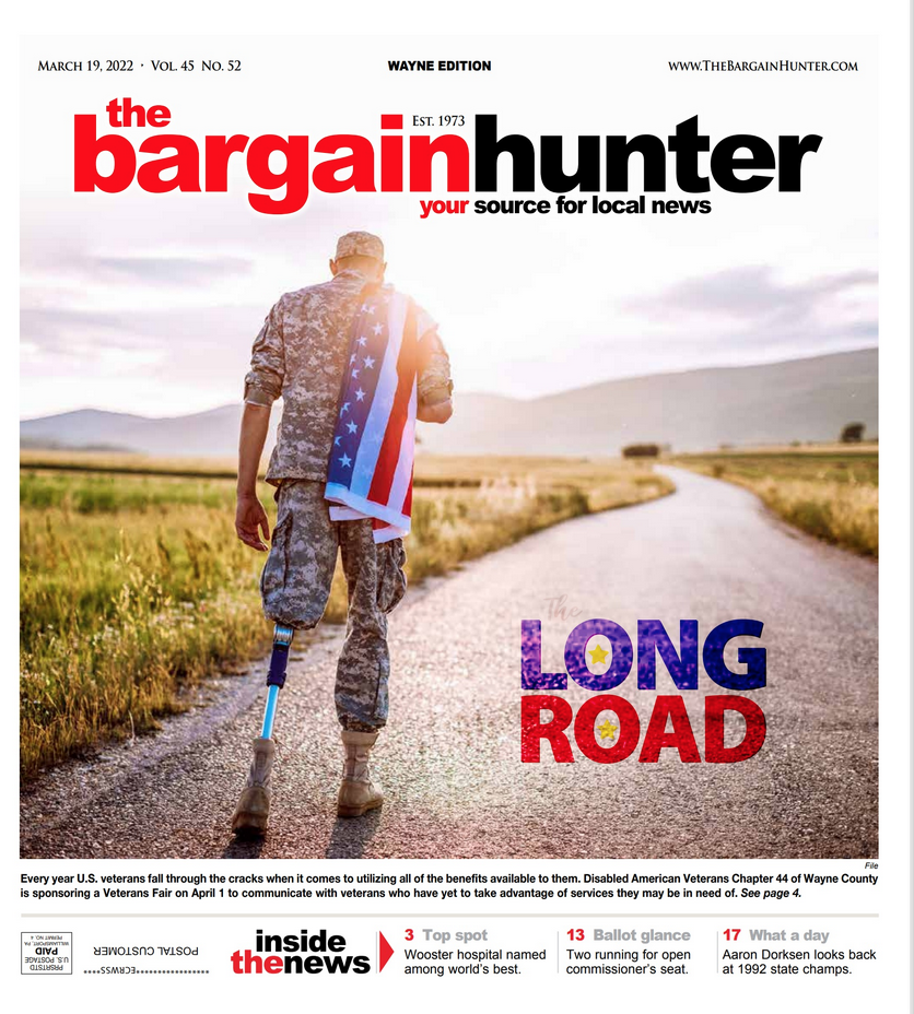 A veteran with a prosthetic leg walks away on a country road, carrying an American flag draped over their shoulder.