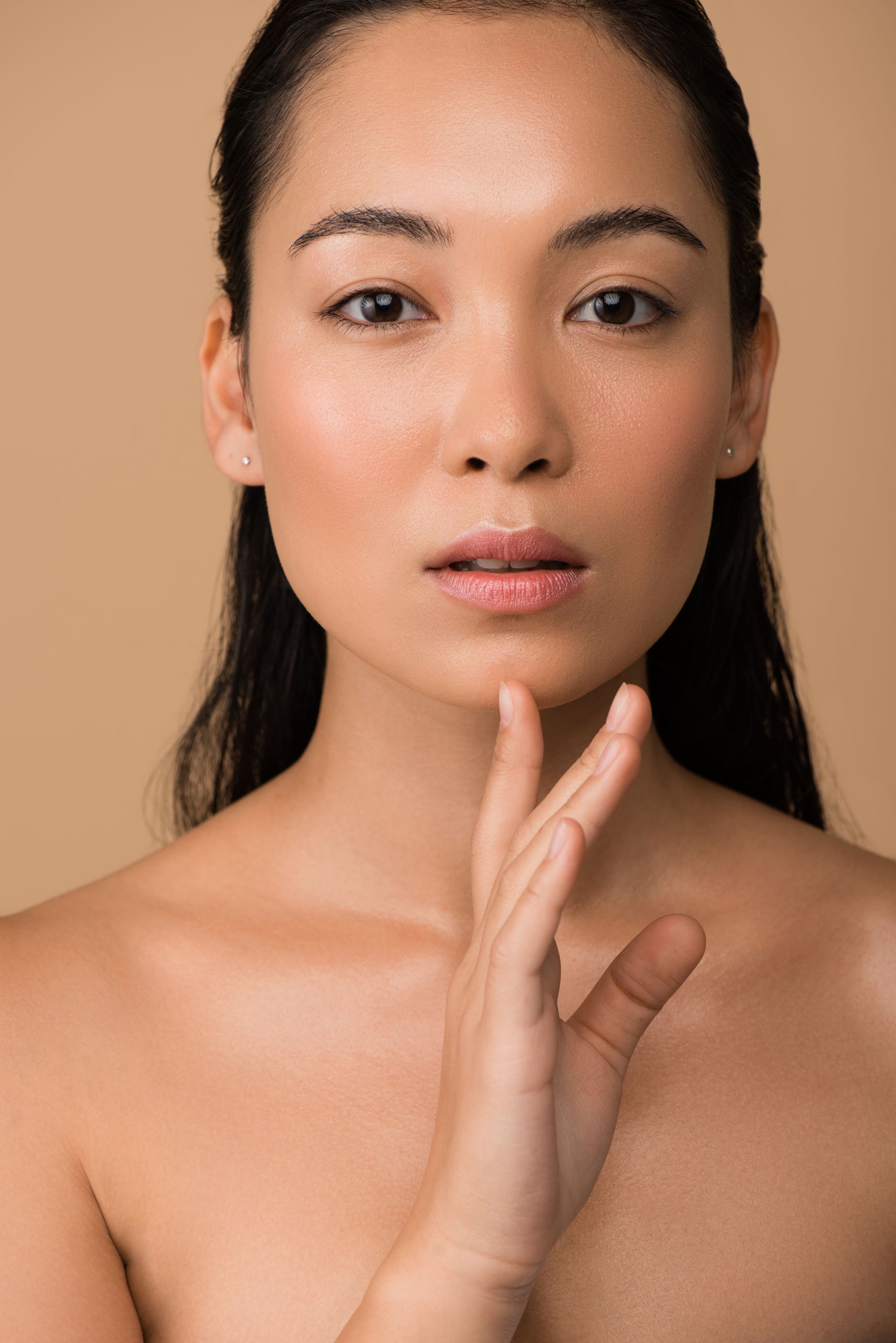 A woman with a neutral expression with her hand on her chin.