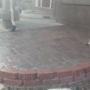 Brick patio with a curved step leading to a covered outdoor walkway and columns