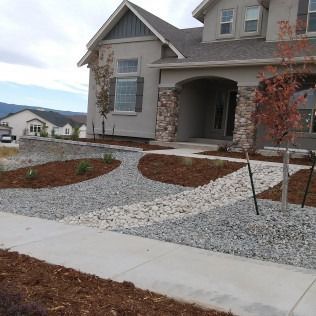 New house exterior with stone accents, gravel landscaping, and a concrete walkway