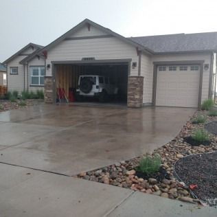 Suburban house with wet driveway and a car parked in the open garage