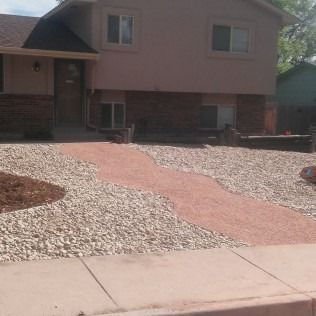 House with a pink stone walkway and gravel landscaping in front.