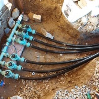 Blue utility pipes and black cables laid in a dirt trench during underground installation 작업