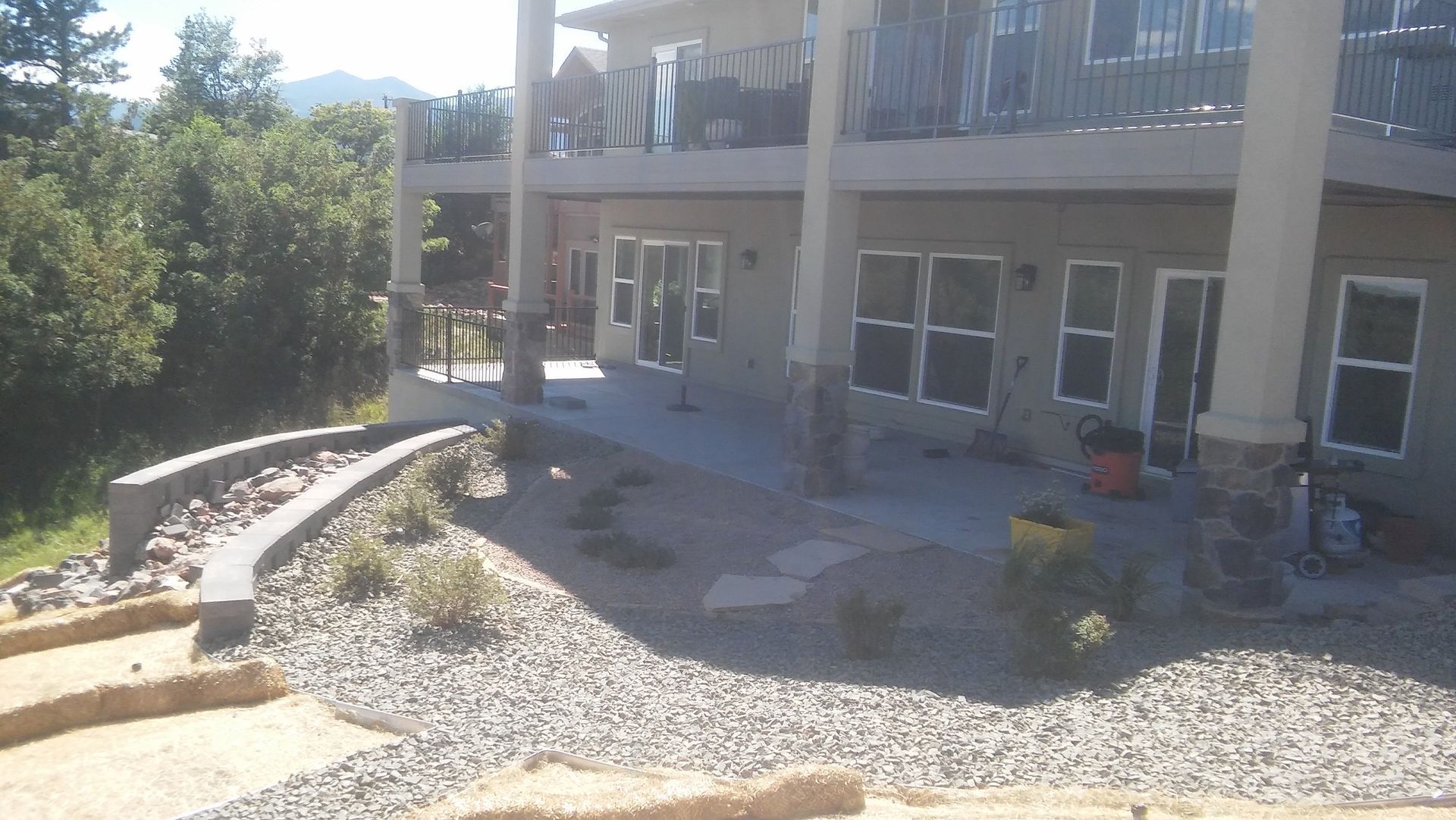 Modern building patio with gravel landscaping, stone edging, and outdoor seating in bright sunlight