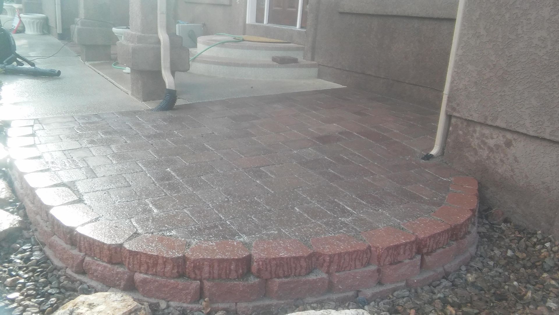 Brick patio ramp at a building entrance with wet pavement and columns