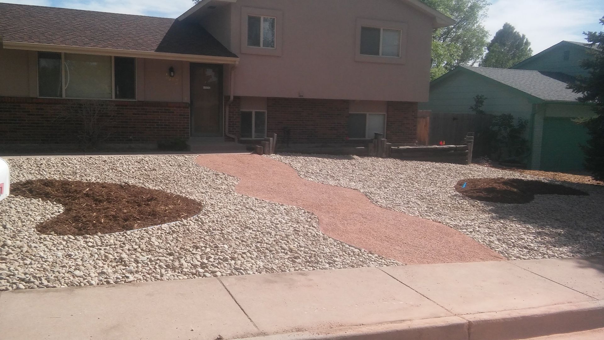 Landscaped front yard with white rocks and red gravel paths in front of a suburban house