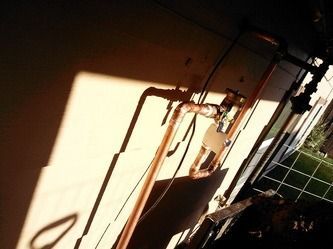 Sunlit indoor wall with pipes and wiring beside a tiled floor and window网