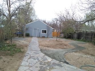 Stone path leading to a small gray shed in a leafless backyard